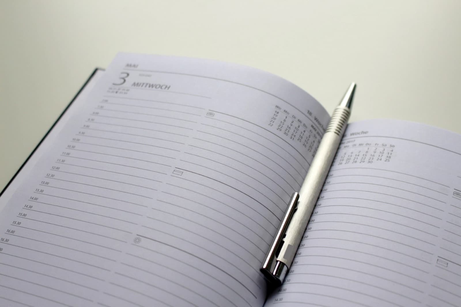 An open daily planner with a pen resting across the pages