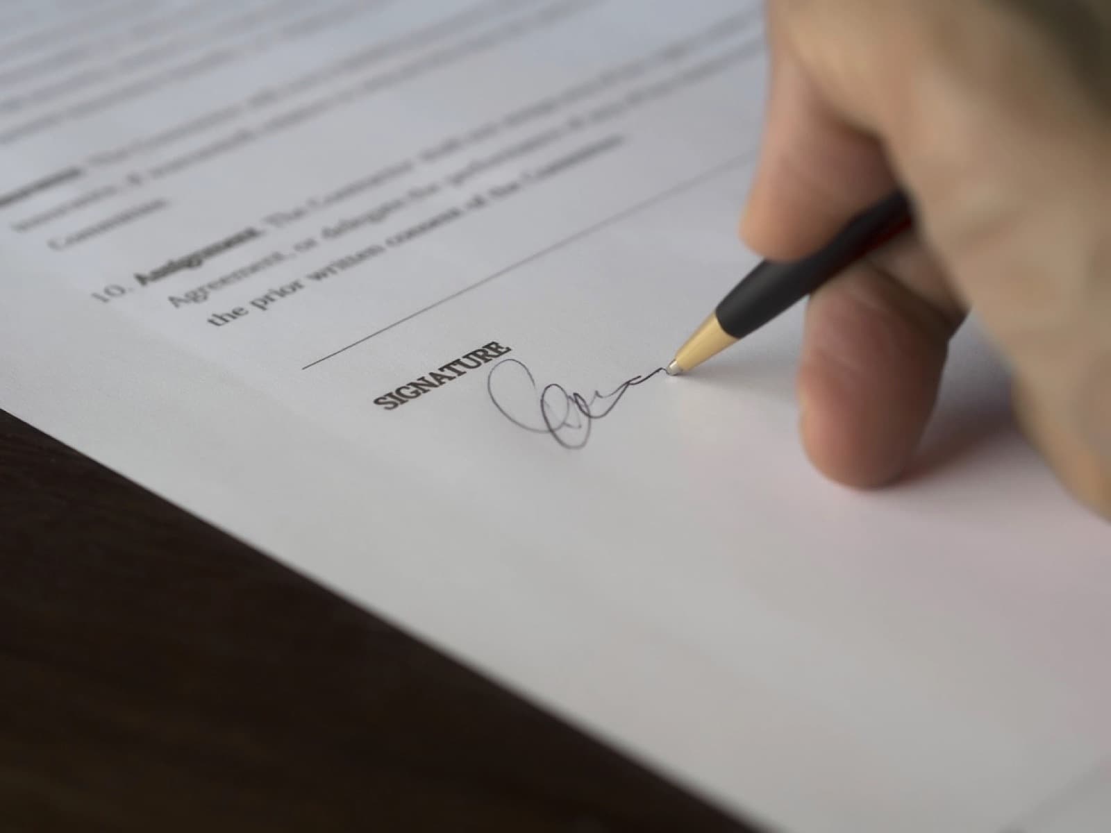 A hand signing a contract with a pen