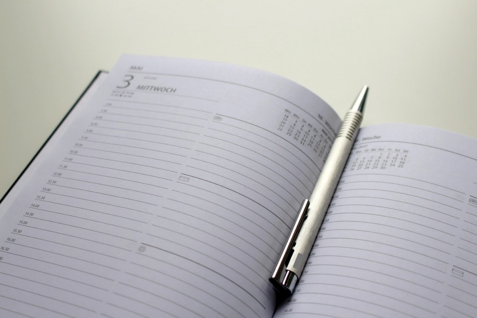 An open daily planner with a pen resting across the pages